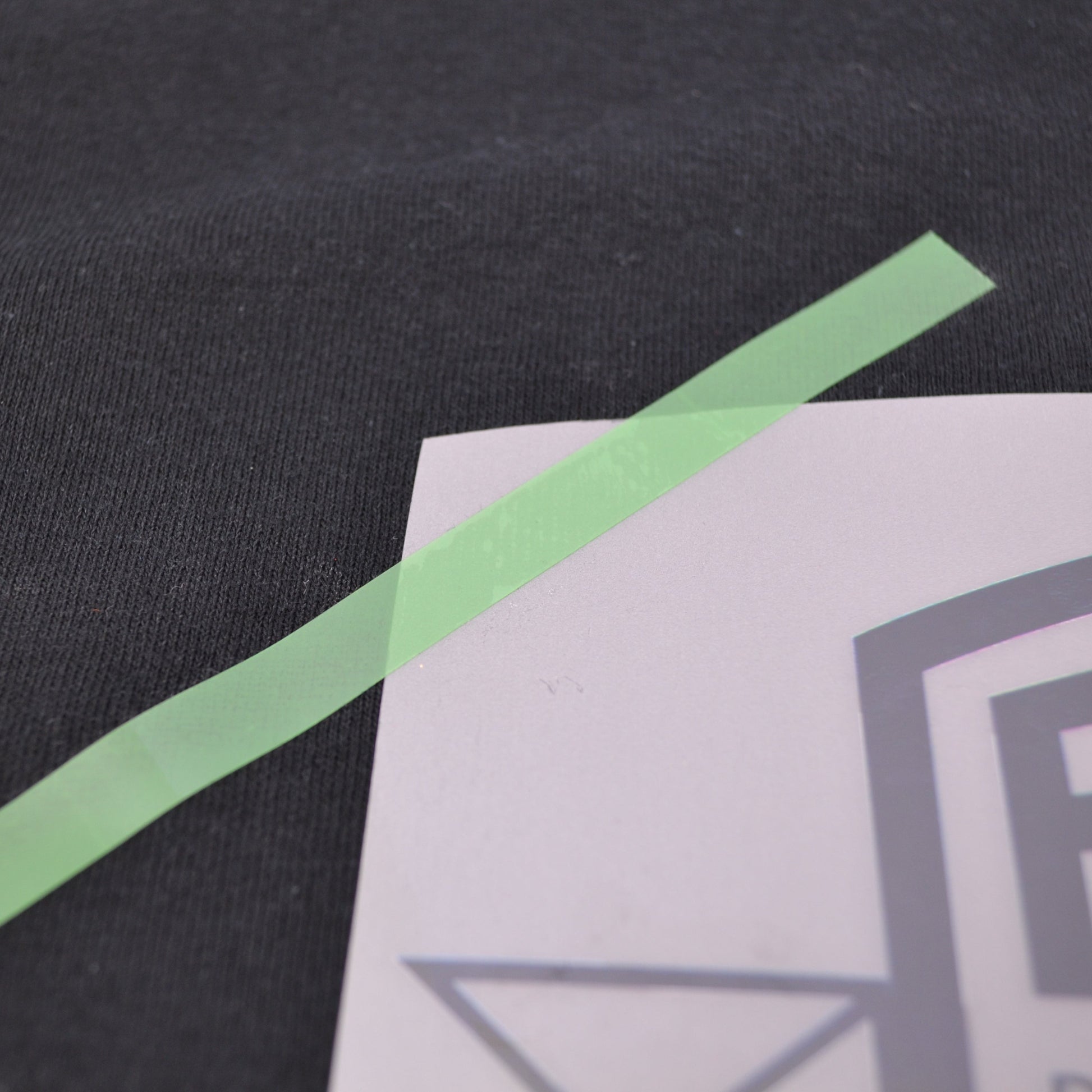 Close-up of a black fabric surface with a green strip and a white card with a logo.