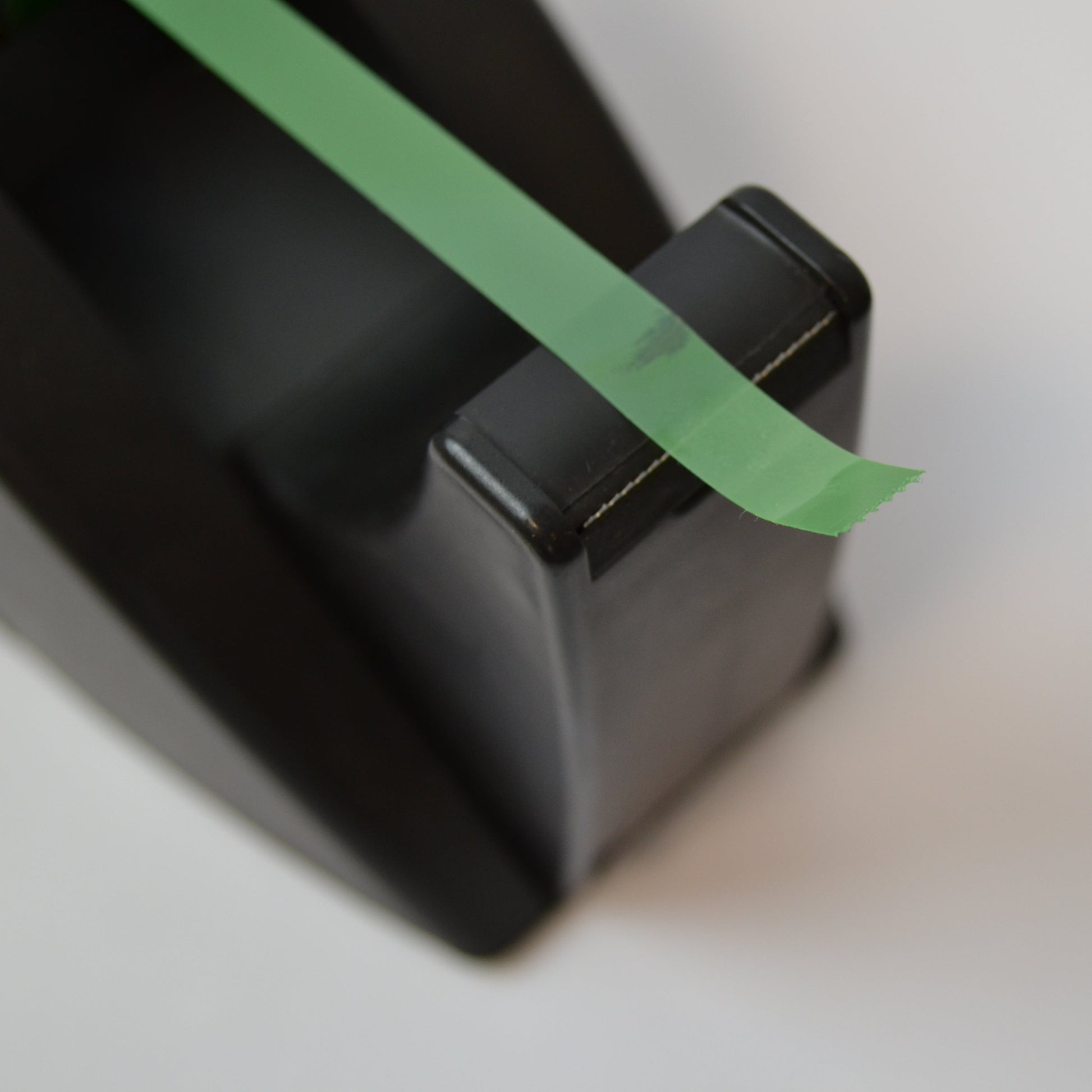 Black electronic device with green tape on a blurred background