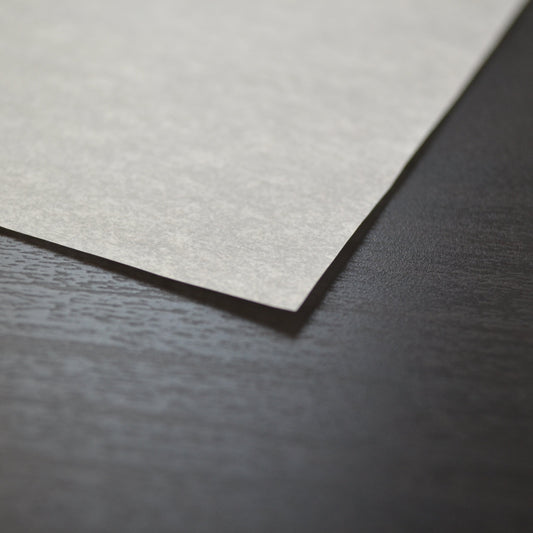 Close-up of a textured beige paper sheet on a dark surface